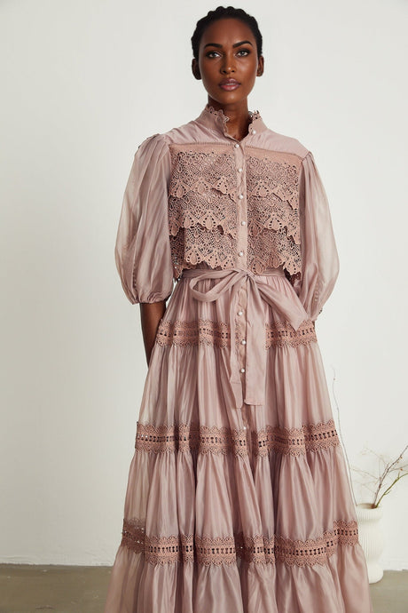 A tiered midi dress with lace detailing and cut out sections featuring a feminine silhouette in a soft color palette