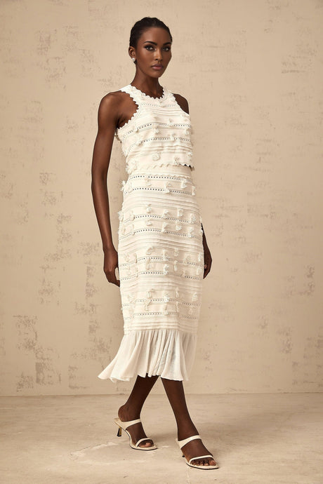 A white knit twopiece outfit consisting of a top and skirt with pointelle trim details The top is sleeveless and the skirt is kneelength Both pieces feature a textured knit pattern and delicate eyelet designs along the edges