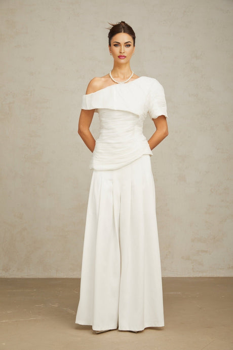 A white matching set featuring a creased top and trousers worn by a female model standing against a plain background