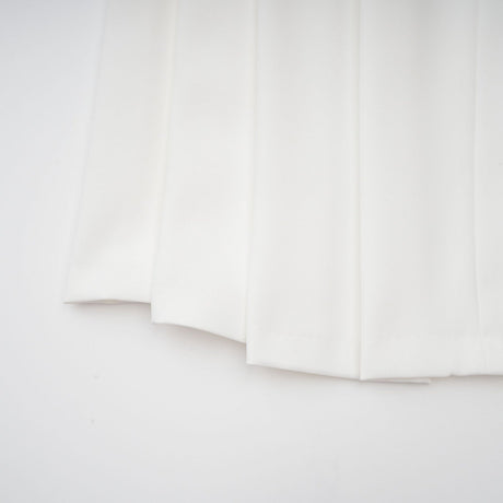 A white matching set featuring a creased top and trousers worn by a model against a plain background