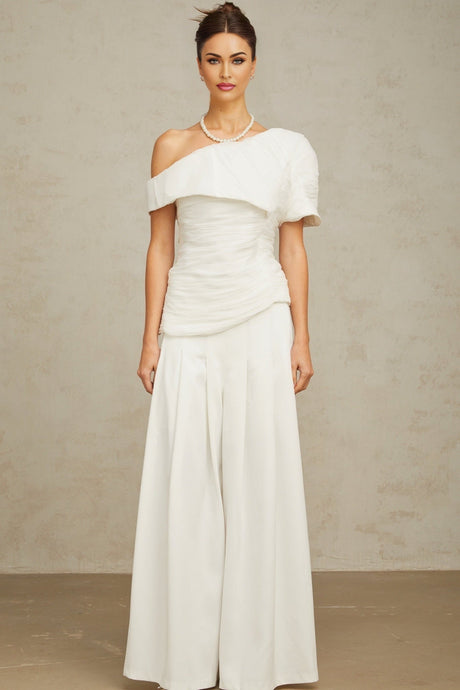 A white matching set featuring a creased top and trousers worn by a model against a plain background