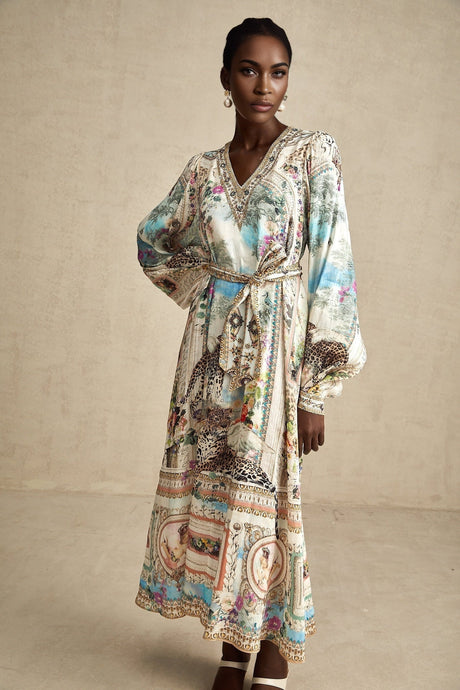 A woman wearing a belted midi dress with a V neckline named Lena standing in a relaxed pose