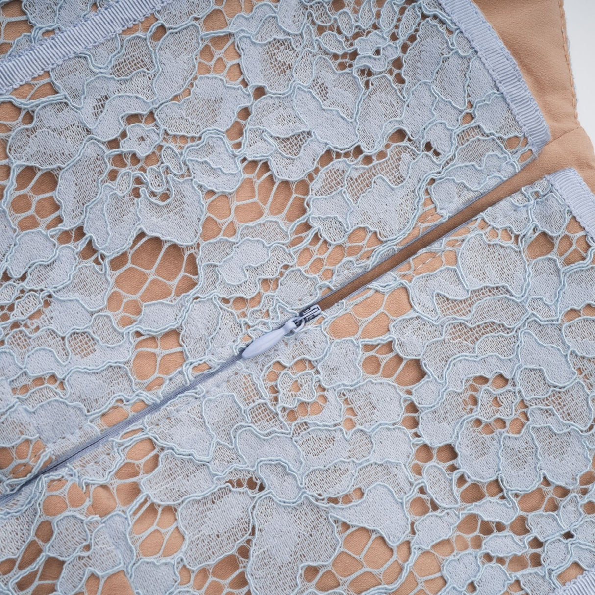A woman wearing a blue midi dress with floral lace pattern and boned bodice