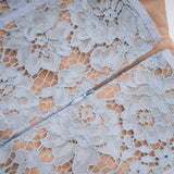 A woman wearing a blue midi dress with floral lace pattern and boned bodice