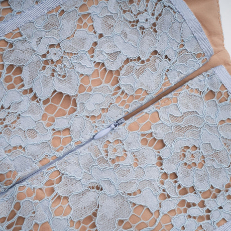 A woman wearing a blue midi dress with floral lace pattern and boned bodice