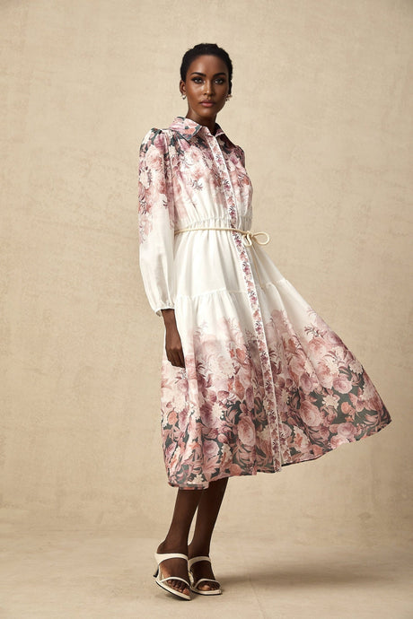 A woman wearing a floral print midi dress with lantern sleeves standing in a casual pose against a plain background