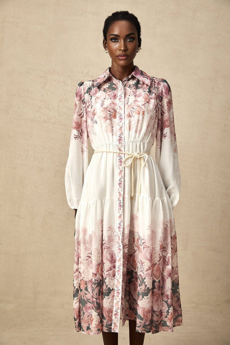 A woman wearing a floral print midi dress with lantern sleeves standing in a relaxed pose against a plain background