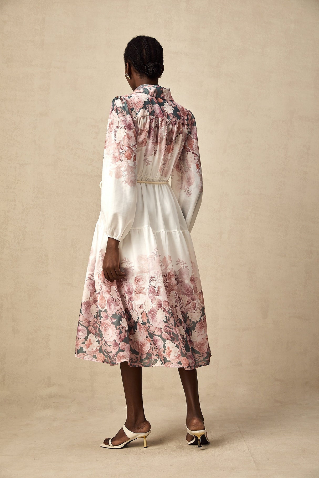 A woman wearing a floral print midi dress with lantern sleeves standing in a relaxed pose against a plain background