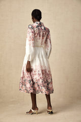 A woman wearing a floral print midi dress with lantern sleeves standing in a relaxed pose against a plain background