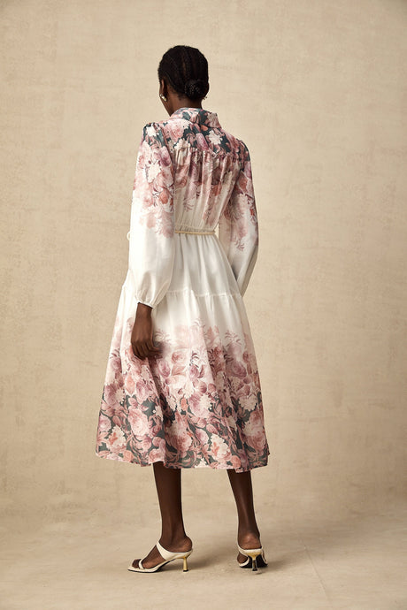 A woman wearing a floral print midi dress with lantern sleeves standing in a relaxed pose against a plain background