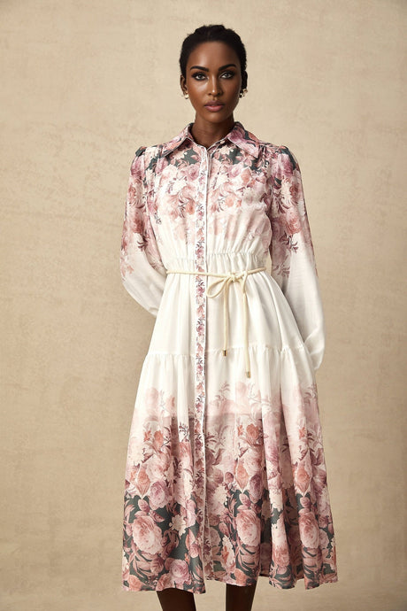 A woman wearing a floral print midi dress with lantern sleeves standing in a relaxed pose against a plain background