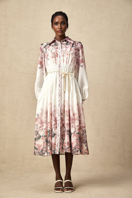 A woman wearing a floral print midi dress with lantern sleeves standing in a relaxed pose