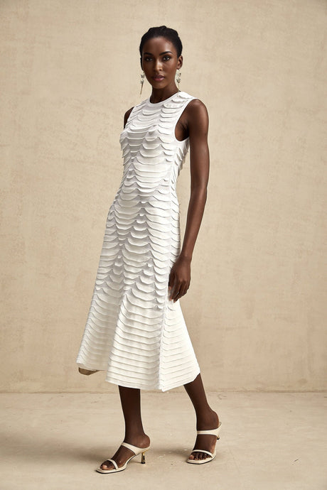 A woman wearing a formfitting snake pattern midi dress with godet inserts flaring out from the knees