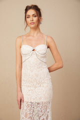 A woman wearing a formfitting white lace midi dress with a crystal embellished bustier top and thin straps