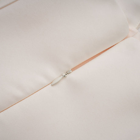 A woman wearing a halterneck tulle midi dress in a light color standing against a plain background