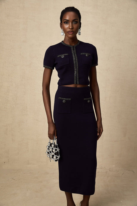 A woman wearing a matching ribbed knit top and skirt set in a light color The top is sleeveless with embellishments and the skirt is knee length Both pieces feature a textured knit pattern