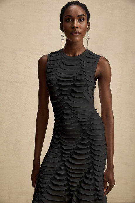 A woman wearing a midi length dress with a snake pattern print and godet inserts for a flared silhouette