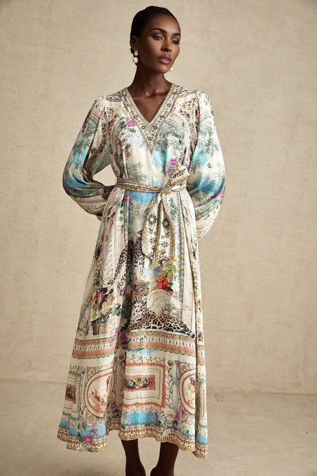 A woman wearing a midi length dress with a V neckline and belt at the waist
