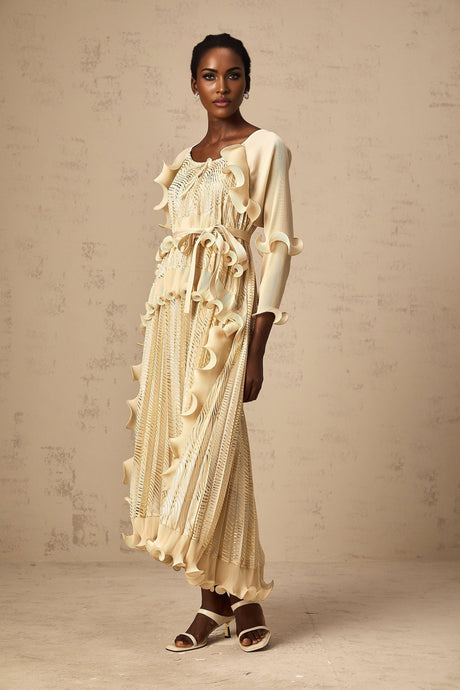 A woman wearing a neutralcolored midi dress with gilded ruffles and a fitted silhouette standing in a relaxed pose