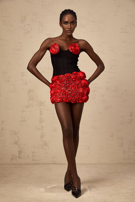 A woman wearing a red matching set consisting of a top and skirt adorned with rose appliques