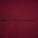 A woman wearing a red midi dress with ruched detailing and a flap design on the front