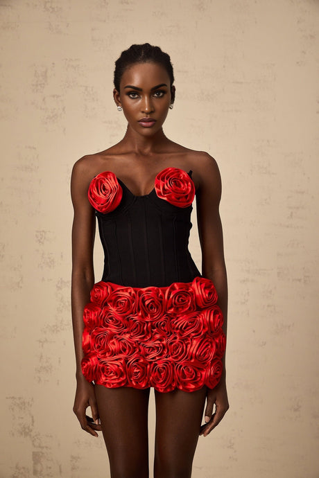 A woman wearing a red twopiece outfit consisting of a top and skirt with rose applique designs matching set