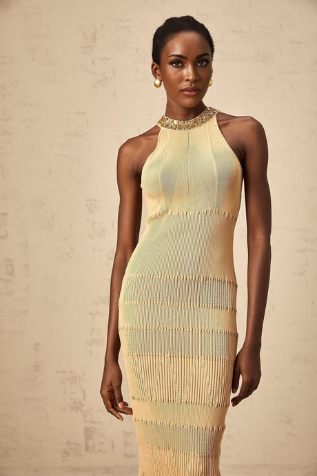 A woman wearing a shimmering sequined midi dress with ribbed texture in a fitted silhouette standing against a plain background