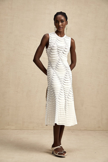 A woman wearing a snakepatterned midi dress with godet panels flaring out from the knees standing in a neutral pose against a plain background