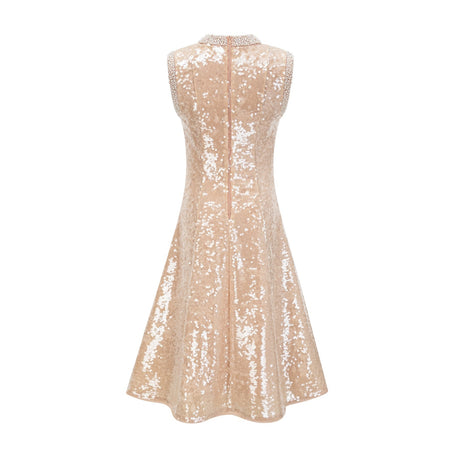 A woman wearing a sparkling midi length dress with sequins and faux pearls adorning the fabric standing in an elegant pose