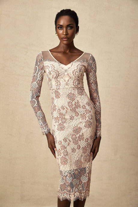 A woman wearing a white fitted midi dress with intricate guipure lace pattern standing against a plain background
