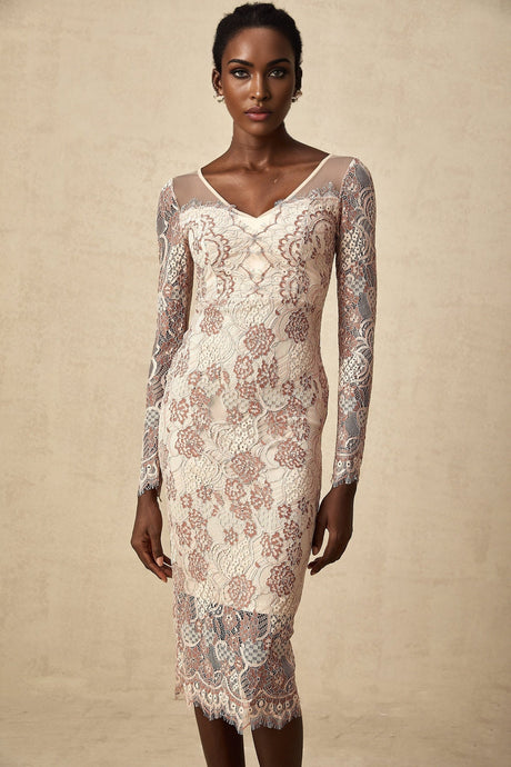 A woman wearing a white formfitting midi dress with intricate guipure lace patterns standing against a plain background