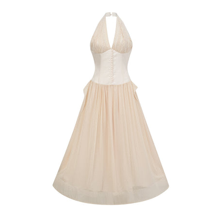 A woman wearing a white halterneck tulle midi dress with a fitted bodice and flowy skirt standing against a plain background