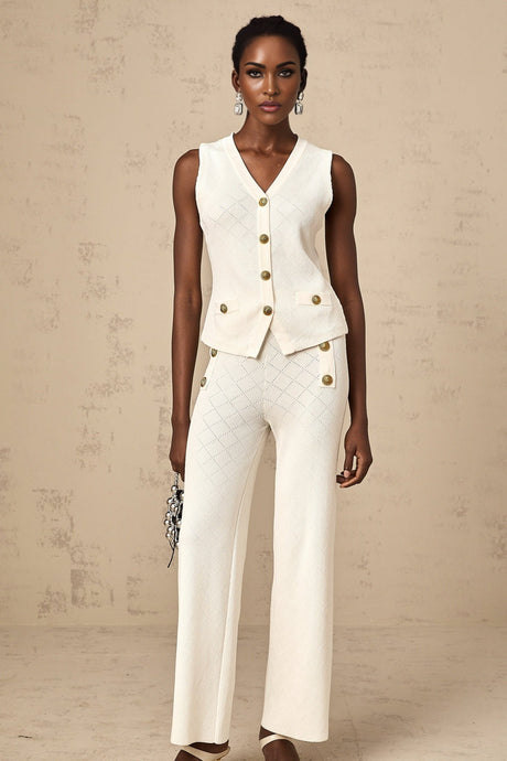 A woman wearing a white knitted matching set consisting of a sleeveless top and loose fitting trousers standing against a plain background