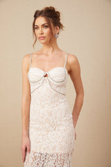 A woman wearing a white lace midi dress with a crystal embellished bustier top featuring thin straps and a fitted silhouette