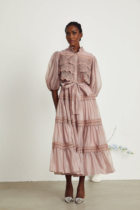 A woman wearing a white lace midi dress with cutout details and tiered skirt standing in a relaxed pose