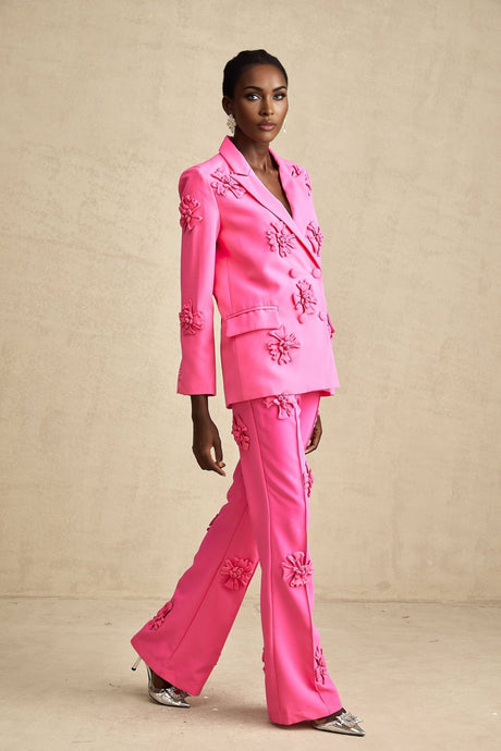 A young girl wearing a pink floral jacket and matching trousers set called AmelieRose The outfit features a delicate flower pattern and is suitable for spring or summer wear