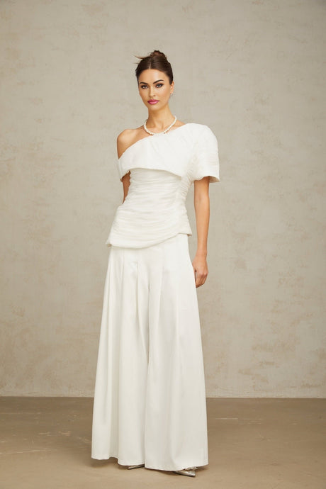 Matching white outfit set featuring a creased top and trousers worn by a model