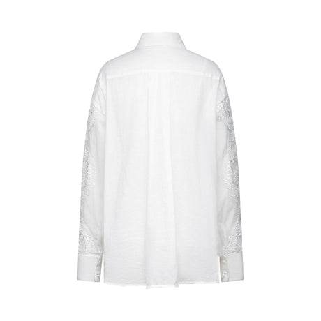 White sleeveless blouse with lace embroidery details and cutout design