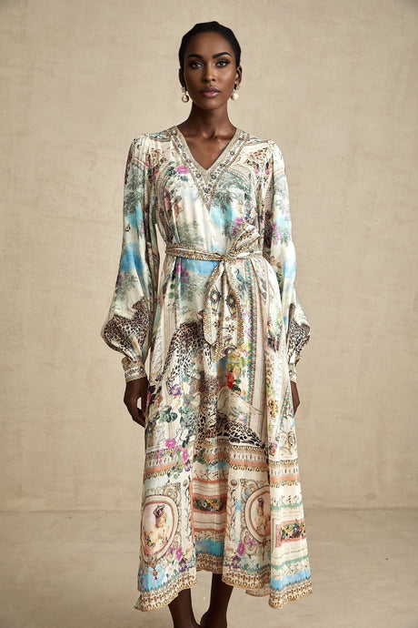 Woman wearing a belted midi dress with Vneck in flowing fabric standing against plain background