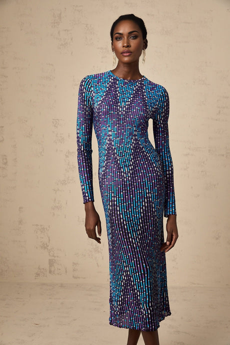 Woman wearing a blue and white zigzag pattern knitted midi dress with long sleeves standing against a plain background