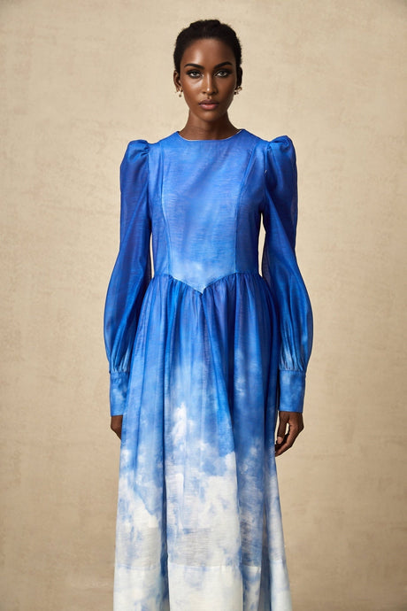Woman wearing a blue gradient pleated midi dress with a flowing silhouette and ombre effect from light to dark blue