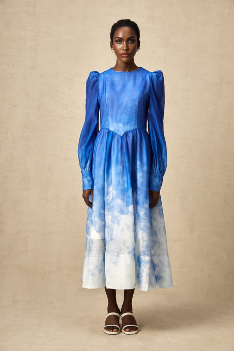 Woman wearing a blue gradient pleated midi dress with a flowing skirt and fitted bodice