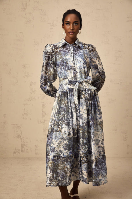 Woman wearing a blue midi dress with floral print pattern standing against a plain background