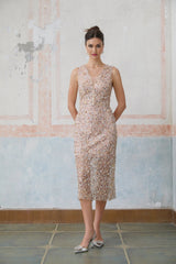 Woman wearing a fitted midi dress with floral embellishments and a Marguerite flower motif