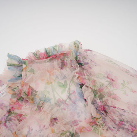 Woman wearing a floral patterned midi dress with ruffled tulle details and a delicate feminine design