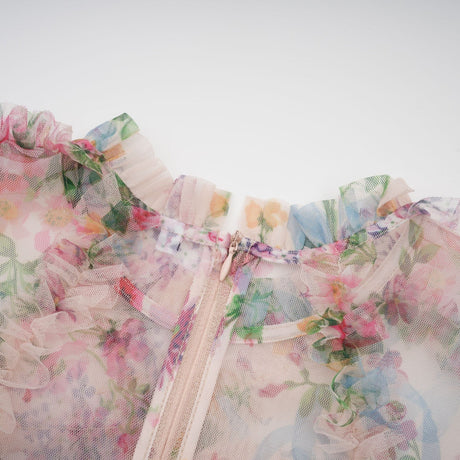Woman wearing a floral patterned midi dress with ruffled tulle details and a flowing skirt