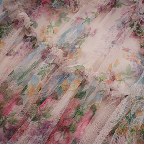 Woman wearing a floral patterned midi dress with ruffles and tulle fabric details