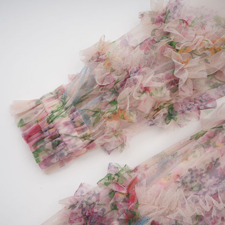 Woman wearing a floral patterned midi dress with tulle fabric and ruffled details