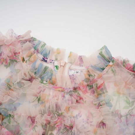 Woman wearing a floral print midi dress with ruffled tulle details and a feminine silhouette