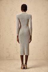 Woman wearing a gold ribbed knit midi dress with pointelle detailing standing in front of a plain background